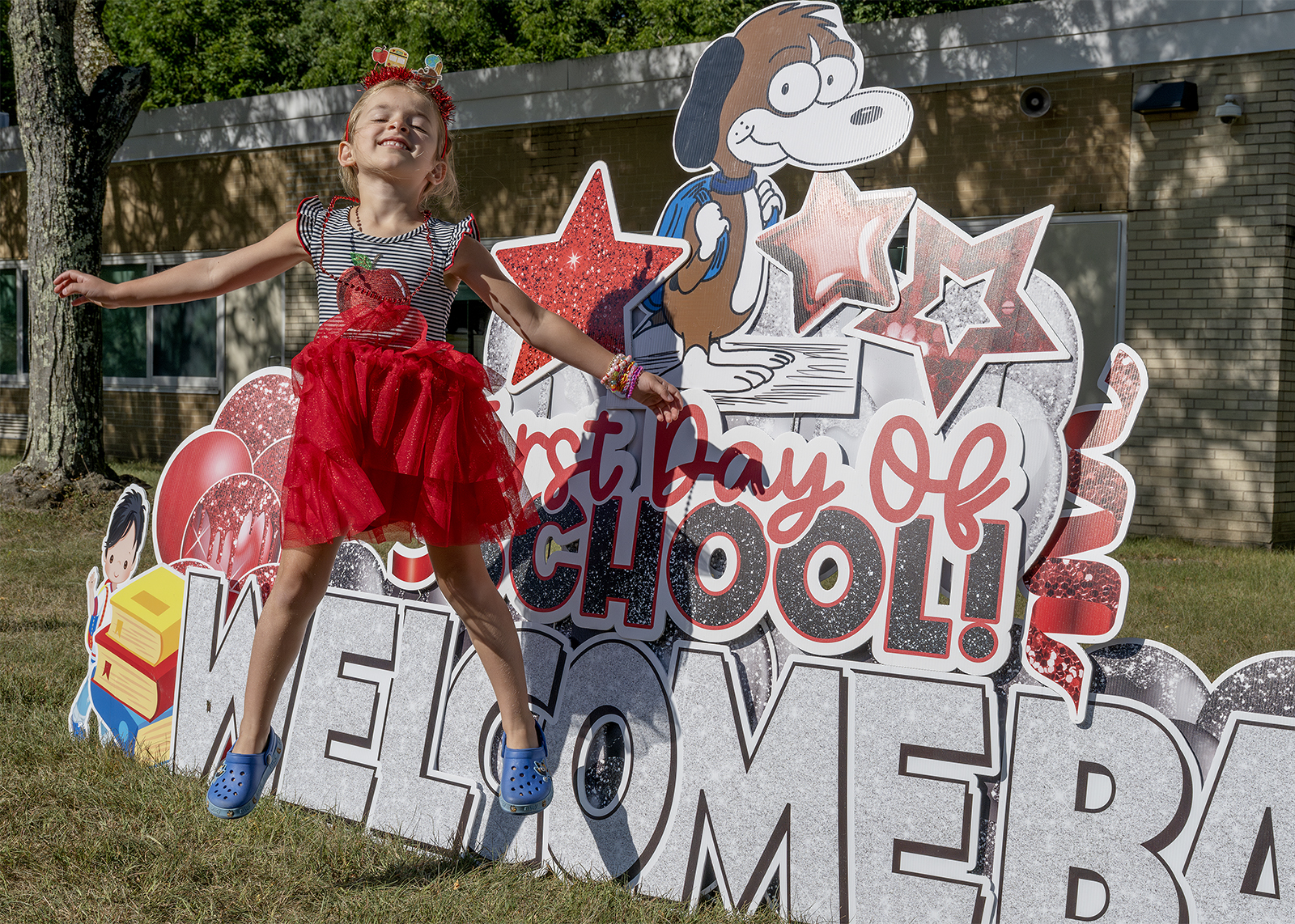 girl jumping in front of welcome back sign