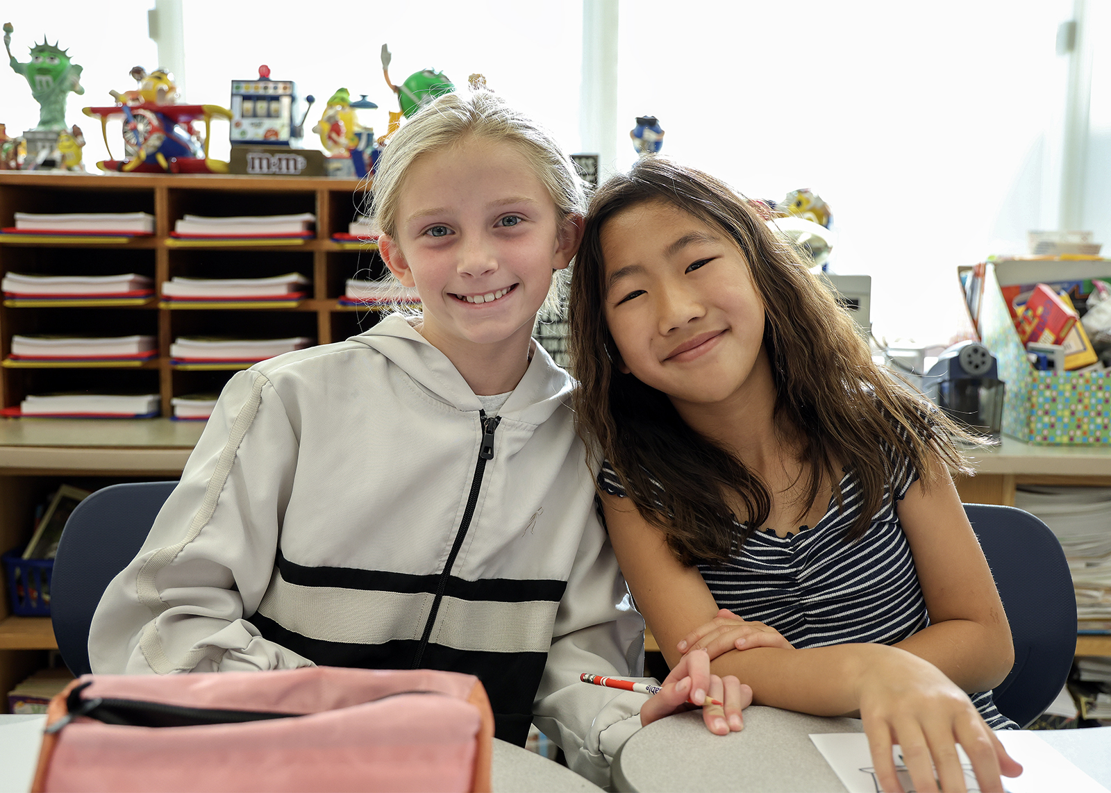 two elementary friends smile in class