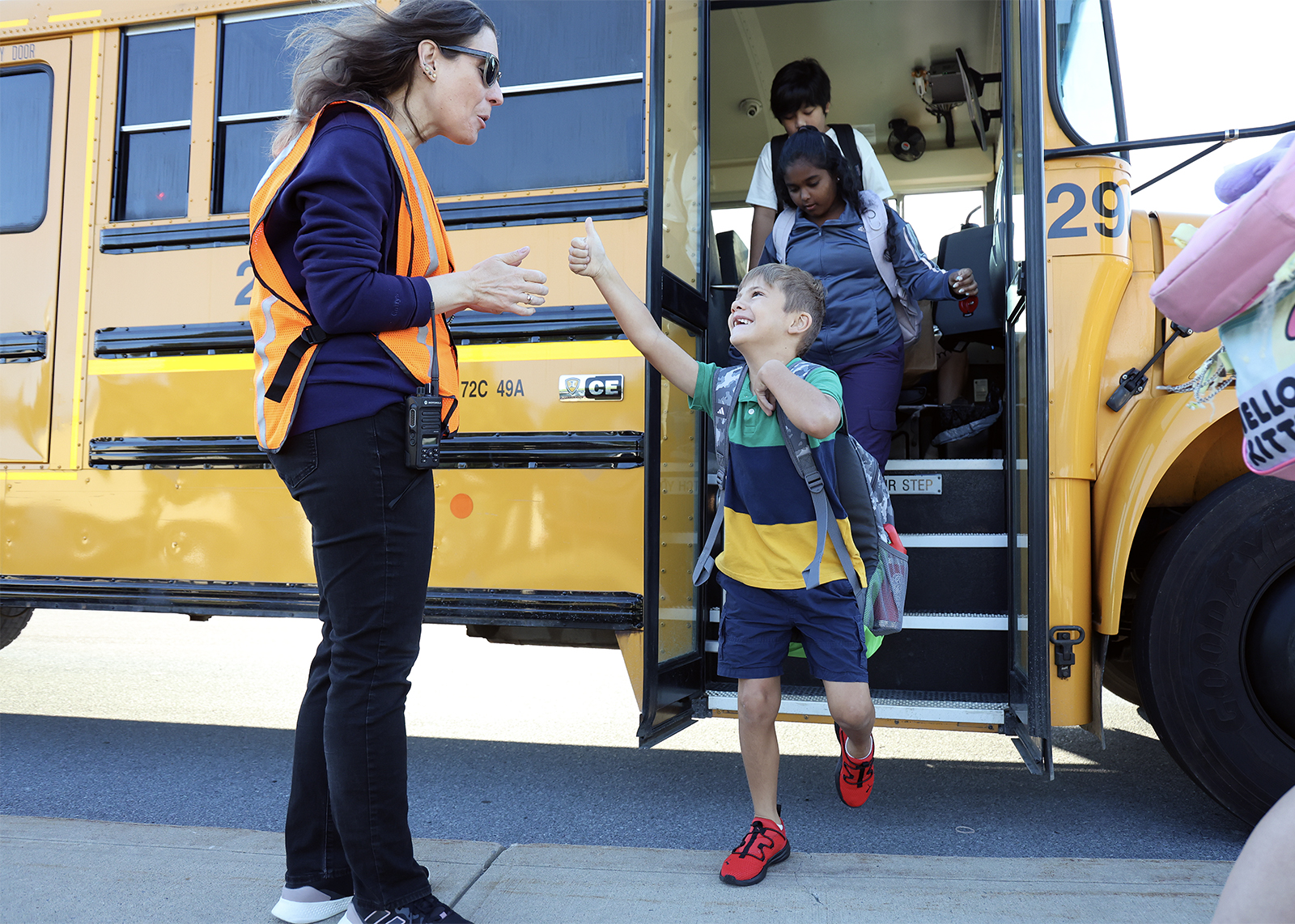 kid smiling and giving a thumbs up coming off bus