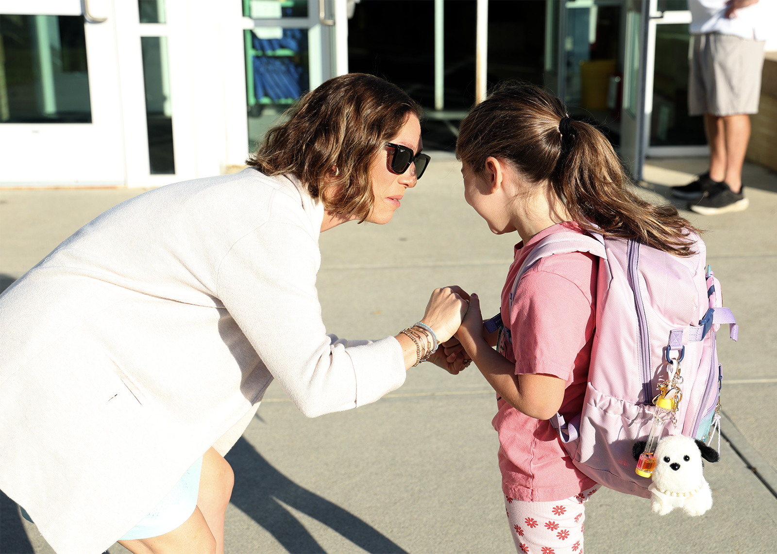 mom and daughter hold hands before going in on first day of school