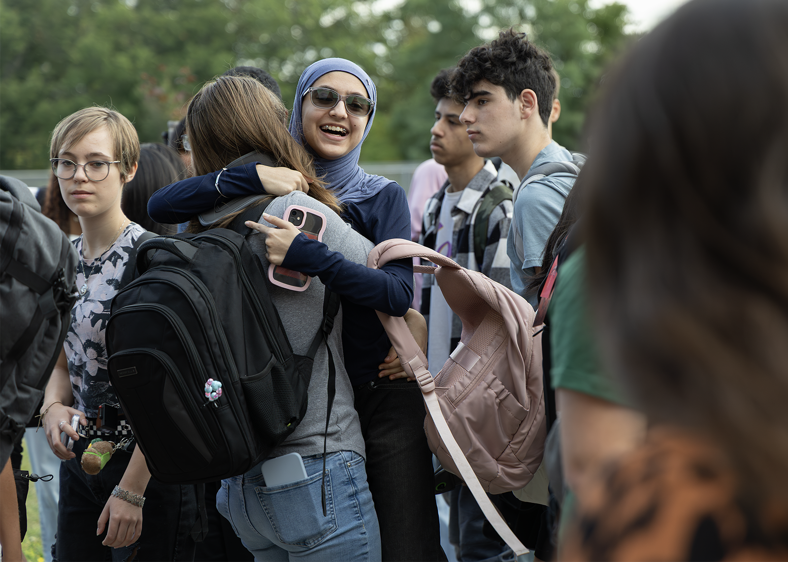 high school friends hug in the middle of a crowd