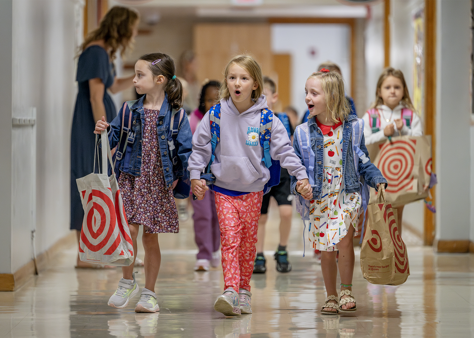 three friends hold hands in hallways with supplies