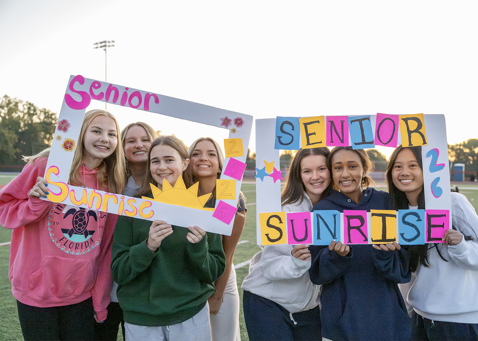 groups of students in cutout poster frames smiling at senior sunrise