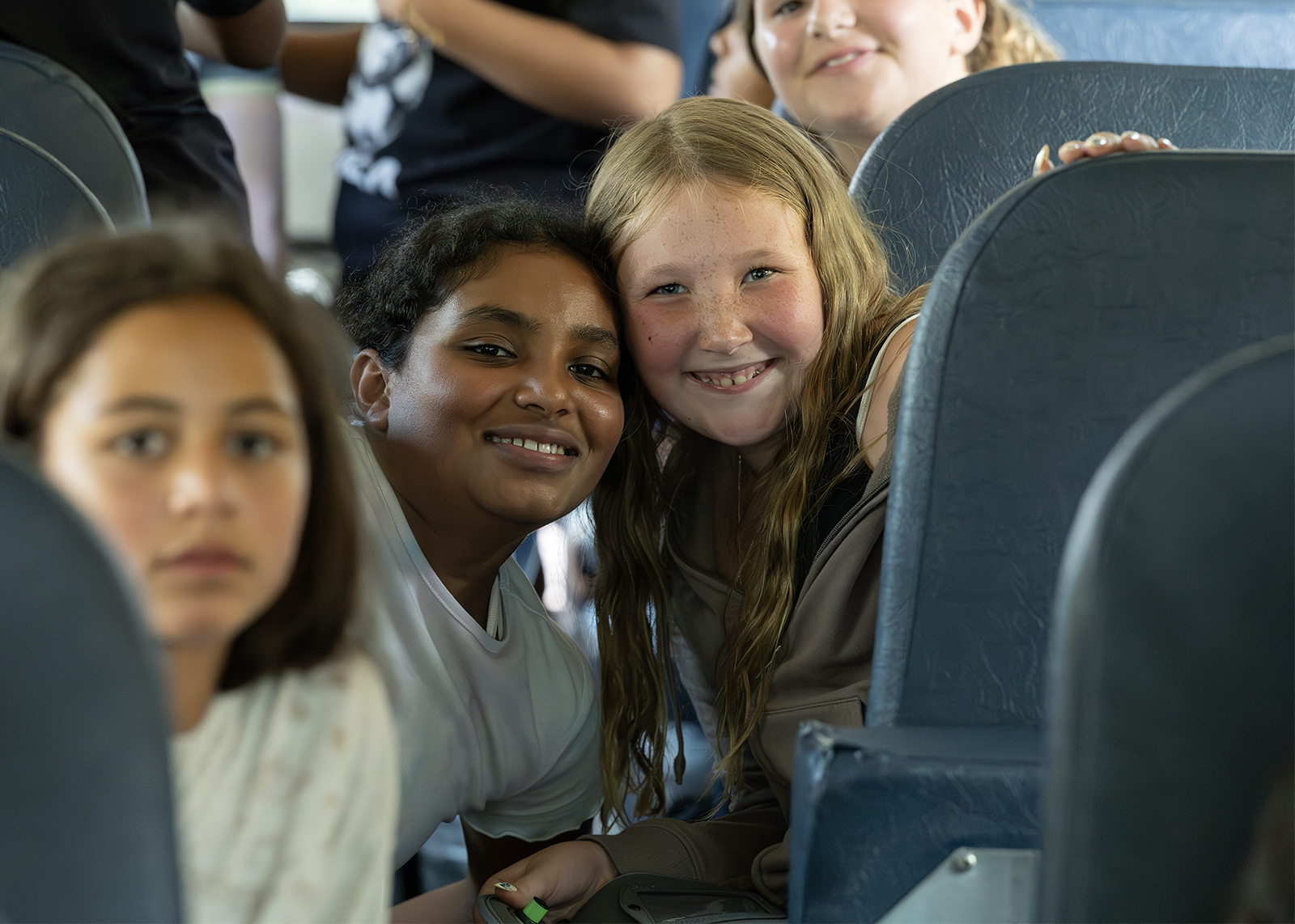 students smile from seats in the back of the bus