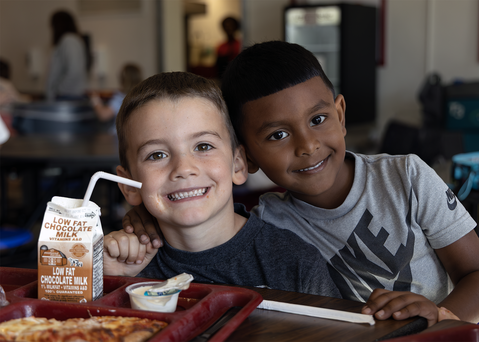 two kindergartners smile at lunch