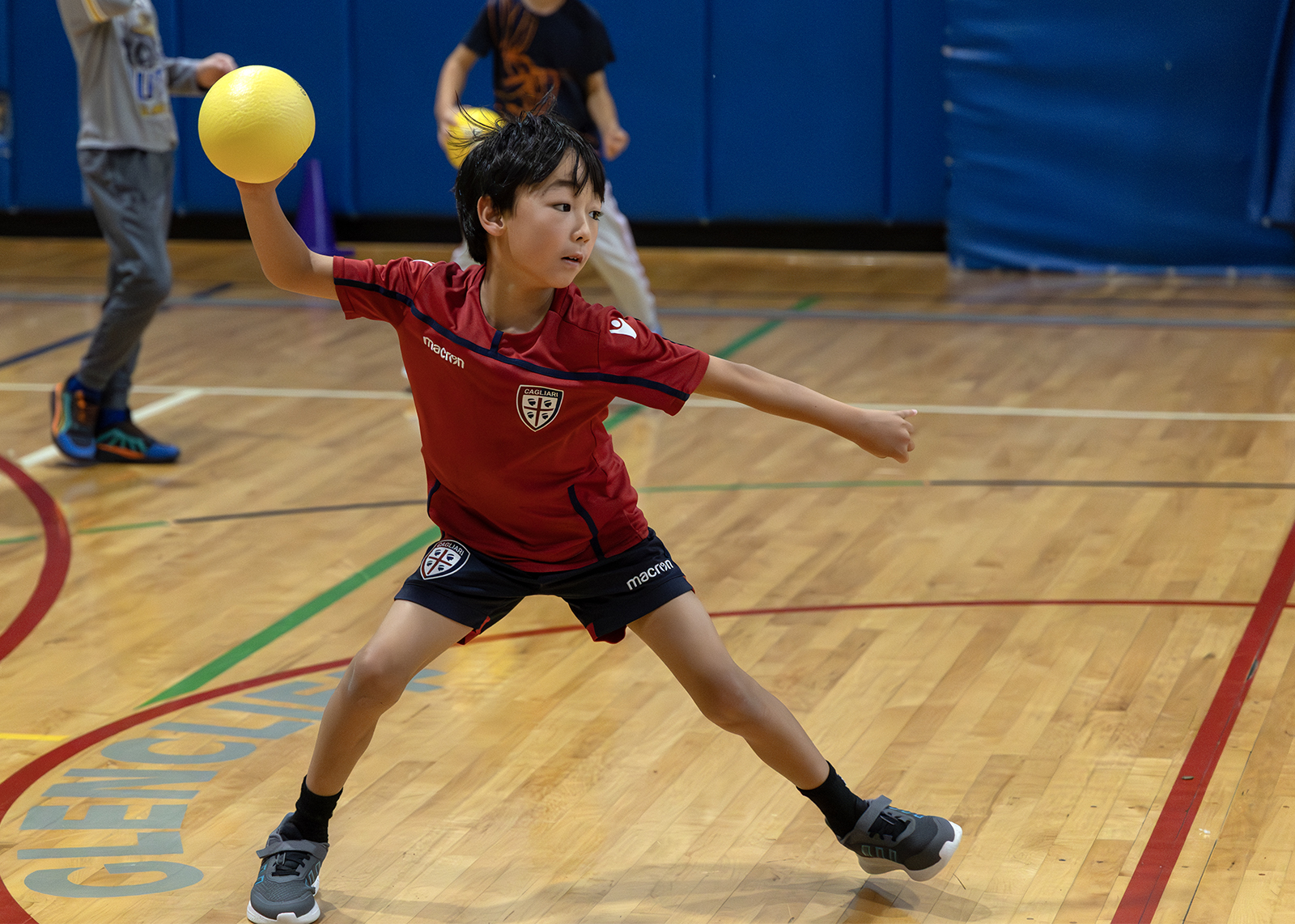 third grader throwing a dodgeball in the gym