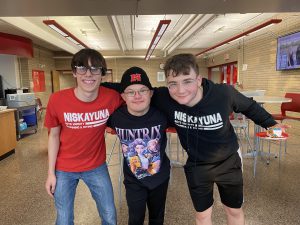 Jooha Song and two boys varsity swim teammates pose in the NHS cafe 
