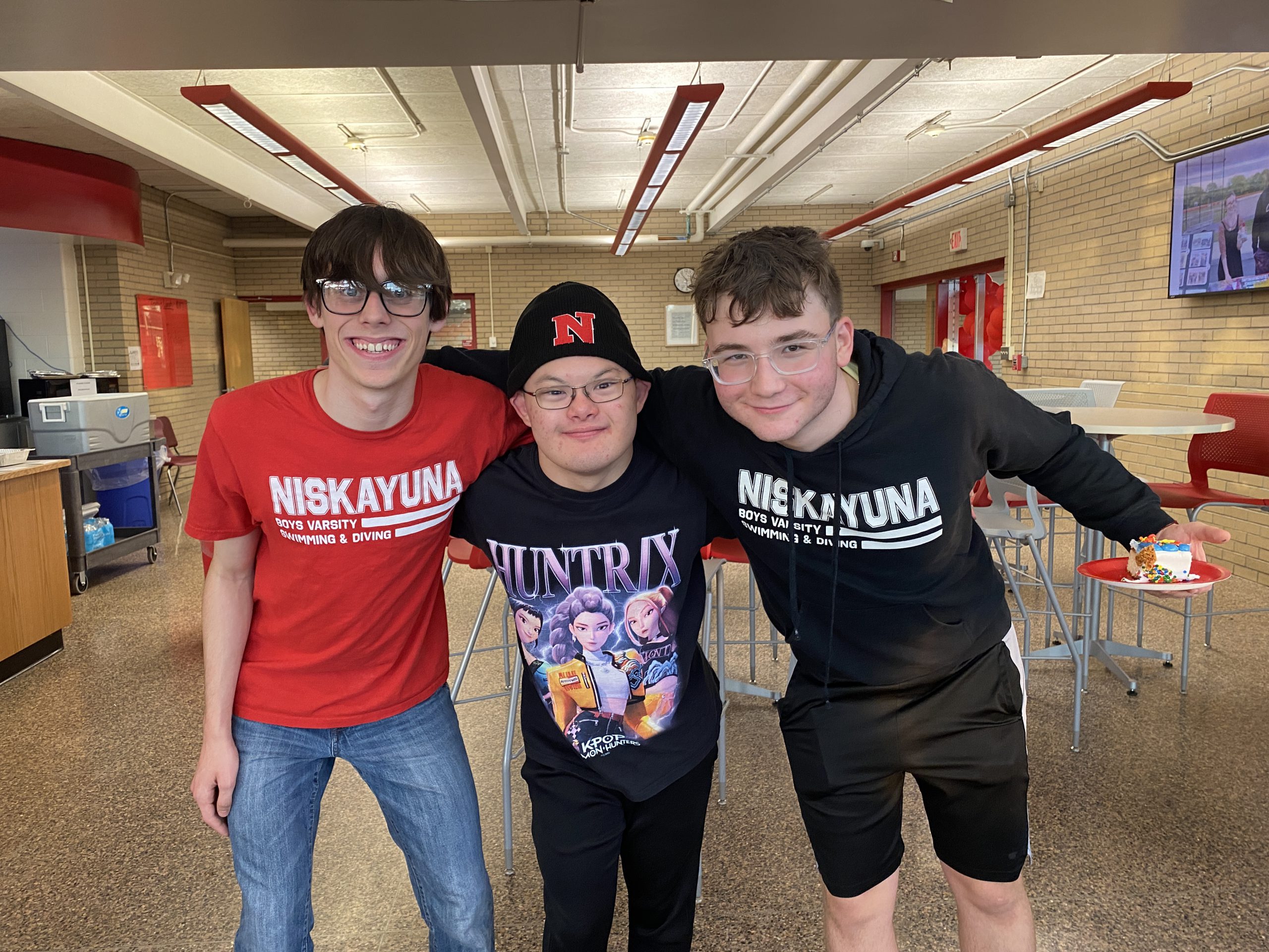 Jooha Song and two boys varsity swim teammates pose in the NHS cafe