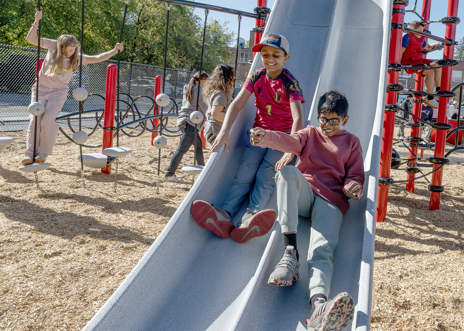 two sixth graders slide next to each other on playground