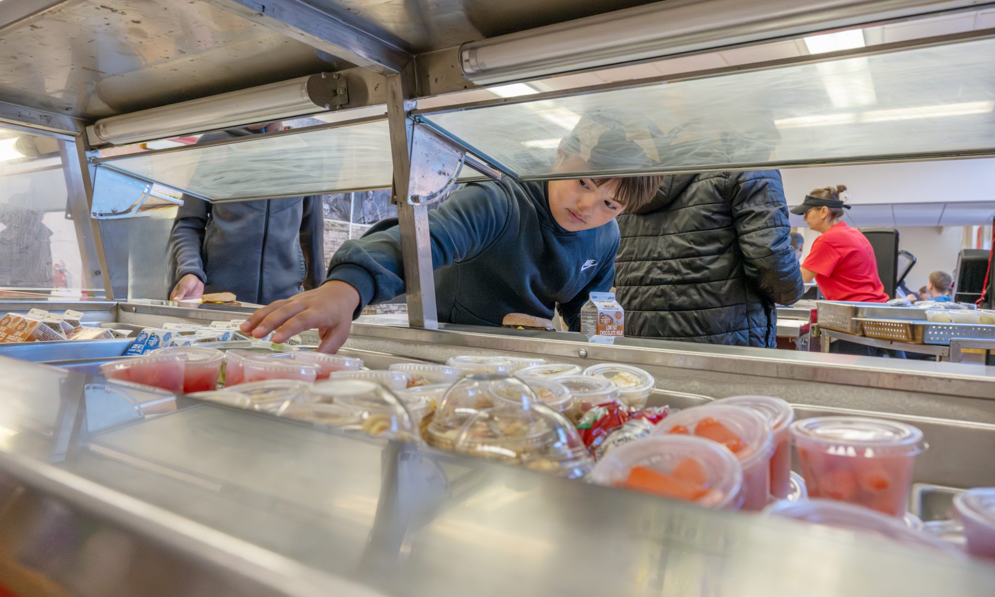 A Van Antwerp Middle School student reaching for a fruit cup in the lunch line