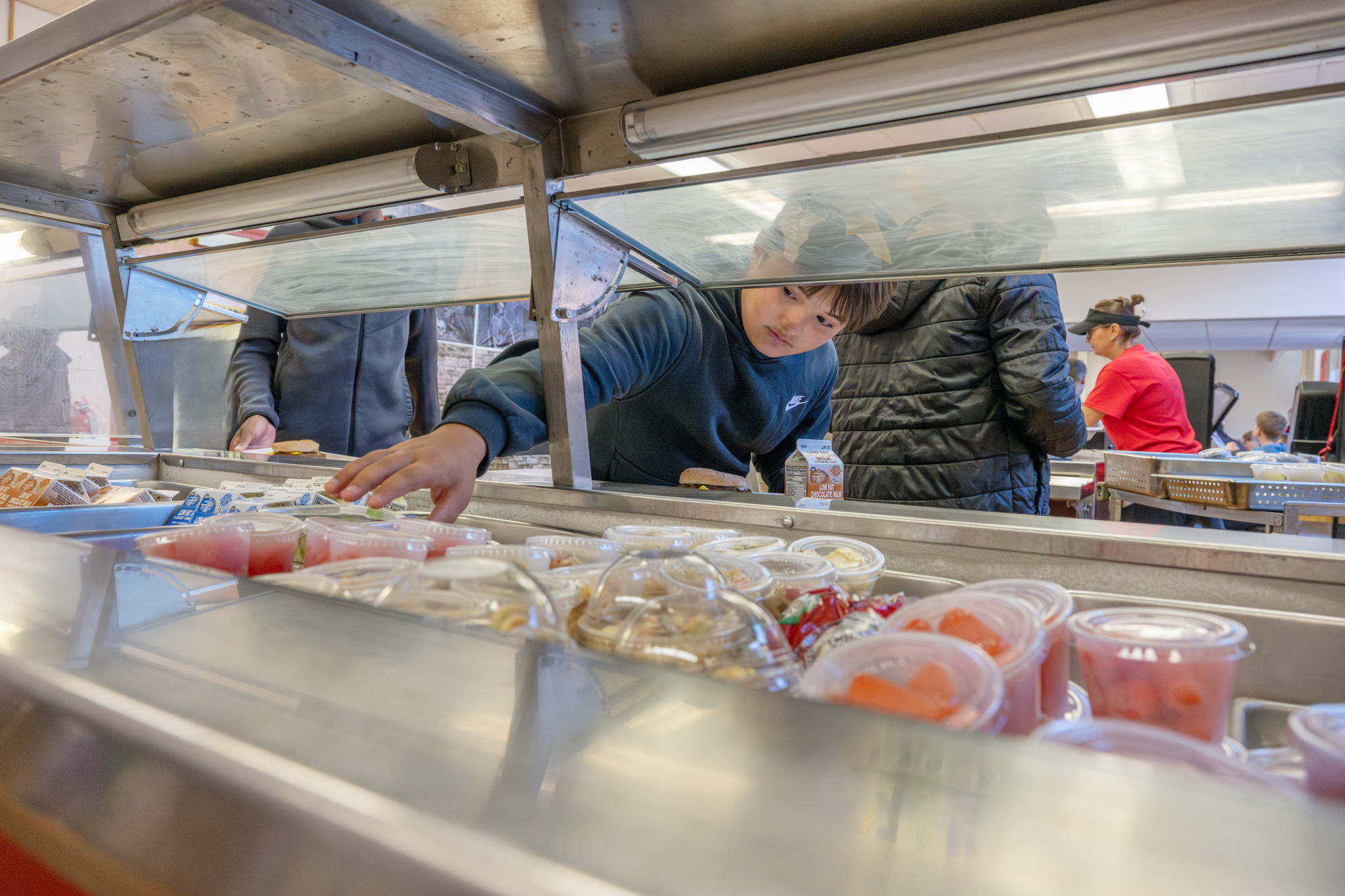 A Van Antwerp Middle School student reaching for a fruit cup in the lunch line