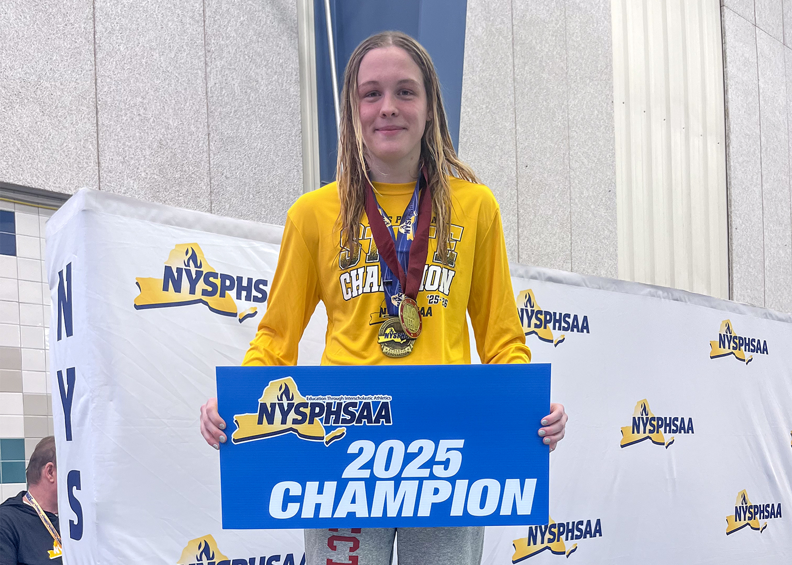 swimmer holding sign that says 2025 champion