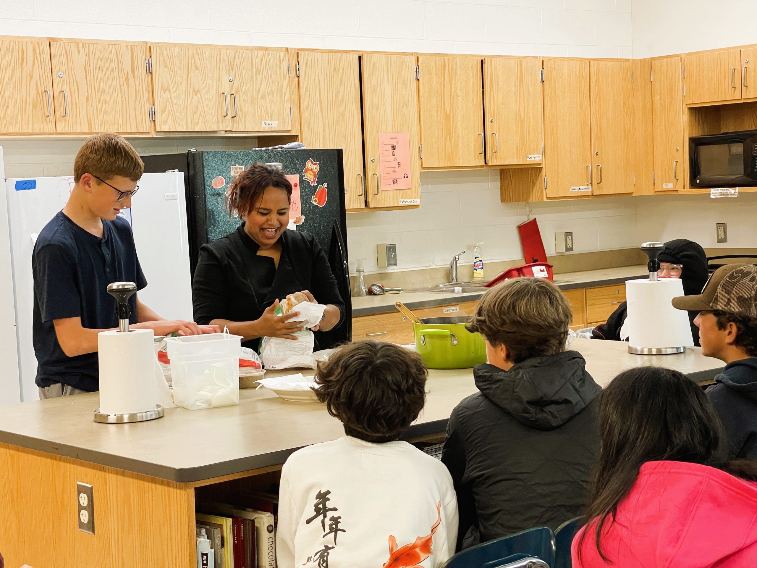 Students watch food being prepared in culinary room.