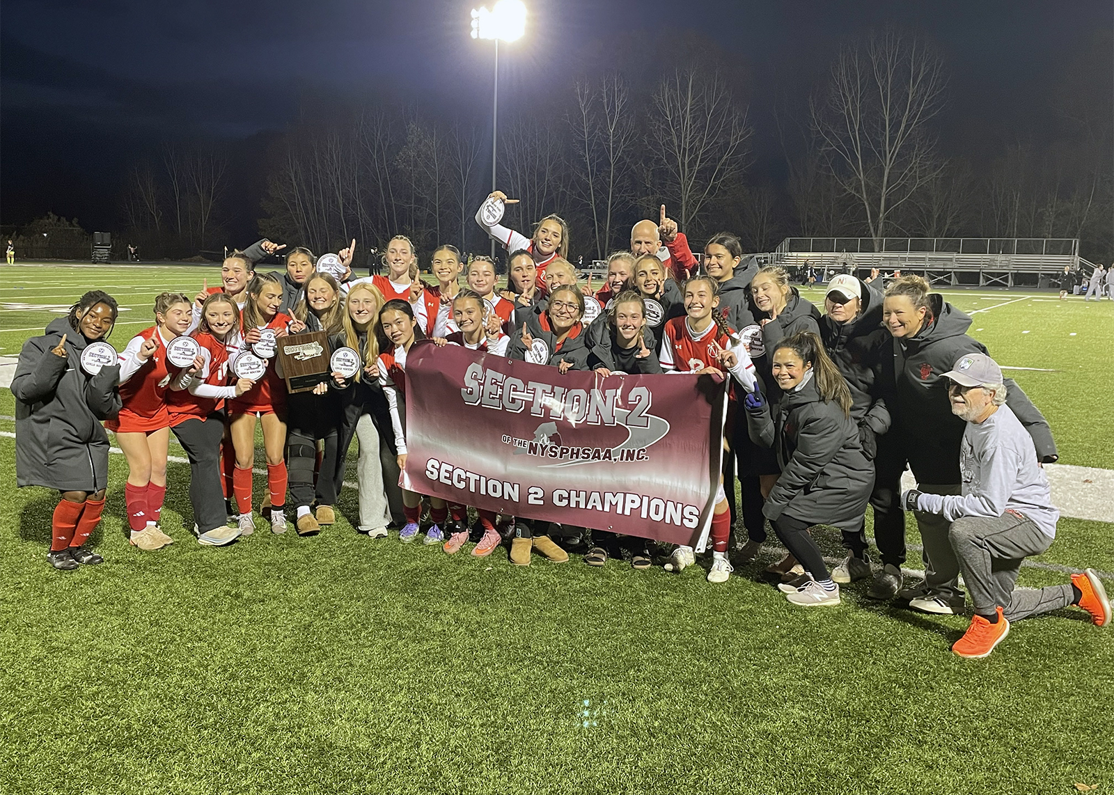 soccer team celebrates with banner that says section 2 champions