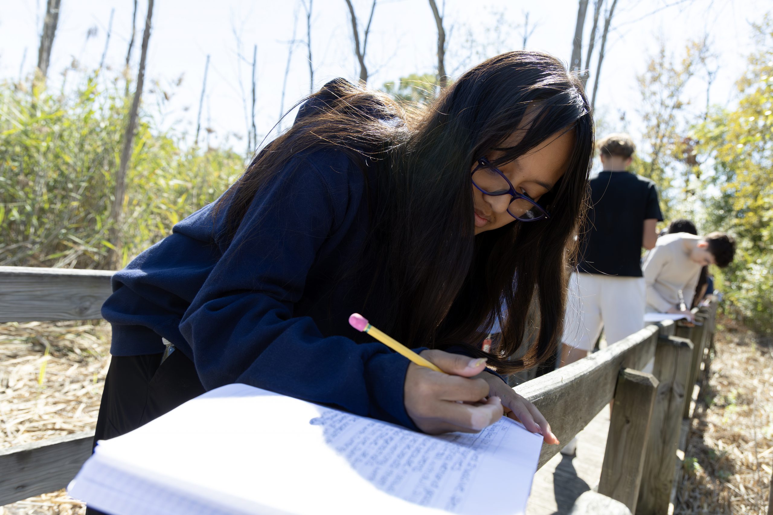 Student takes notes during outside learning experience.