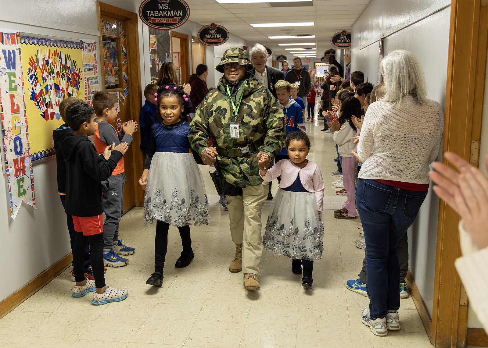 Veterans and children hold hands for indoor parade