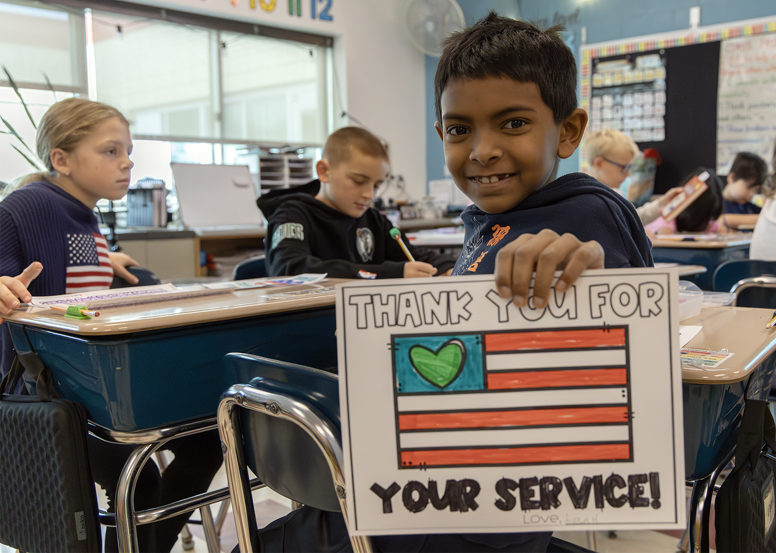 student smiles and holds up sign that says thank you for your service