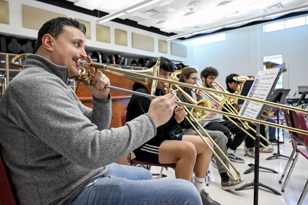 Band teacher Phil Pandori playing a trombone with students