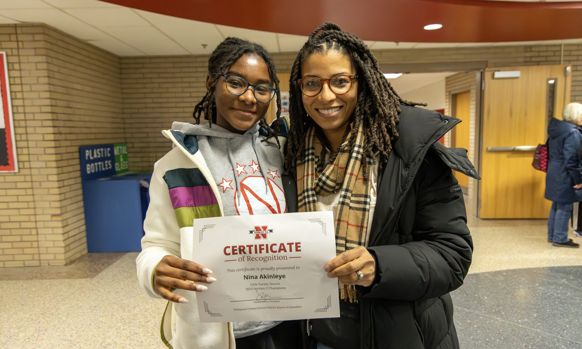 Student poses for group photo with certificate.