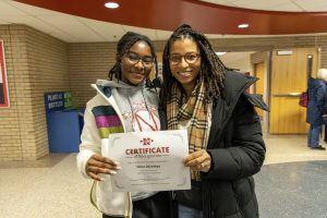 Student poses for group photo with certificate.