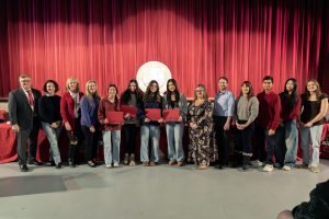 Student-athletes pose for group photo with board members, some students hold awards
