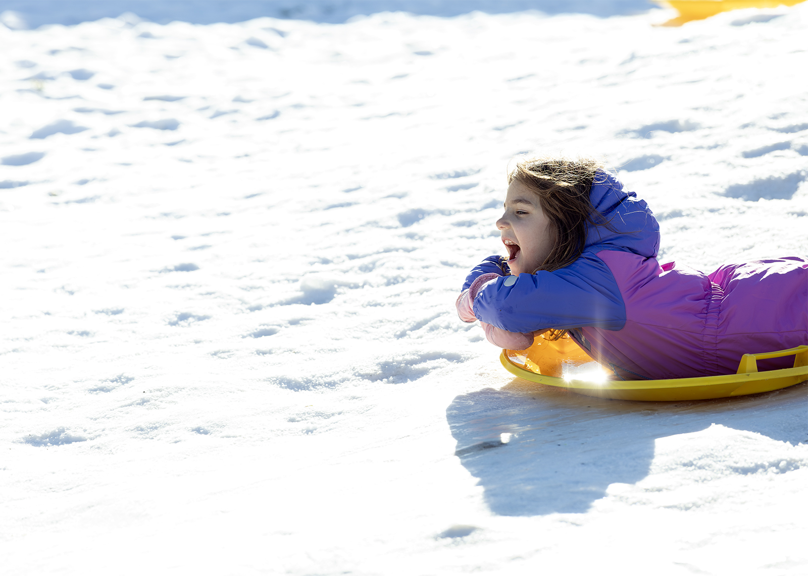 kindergartner riding saucer in snowpants