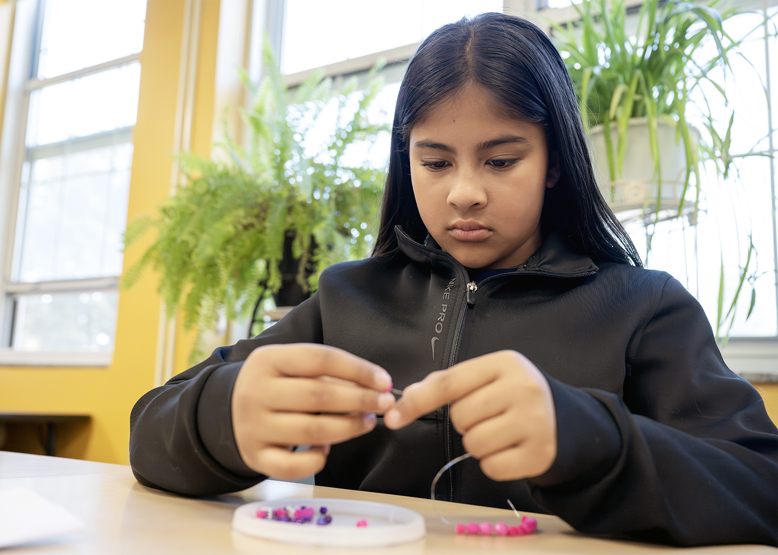 sixth grader concentrating on a bead craft