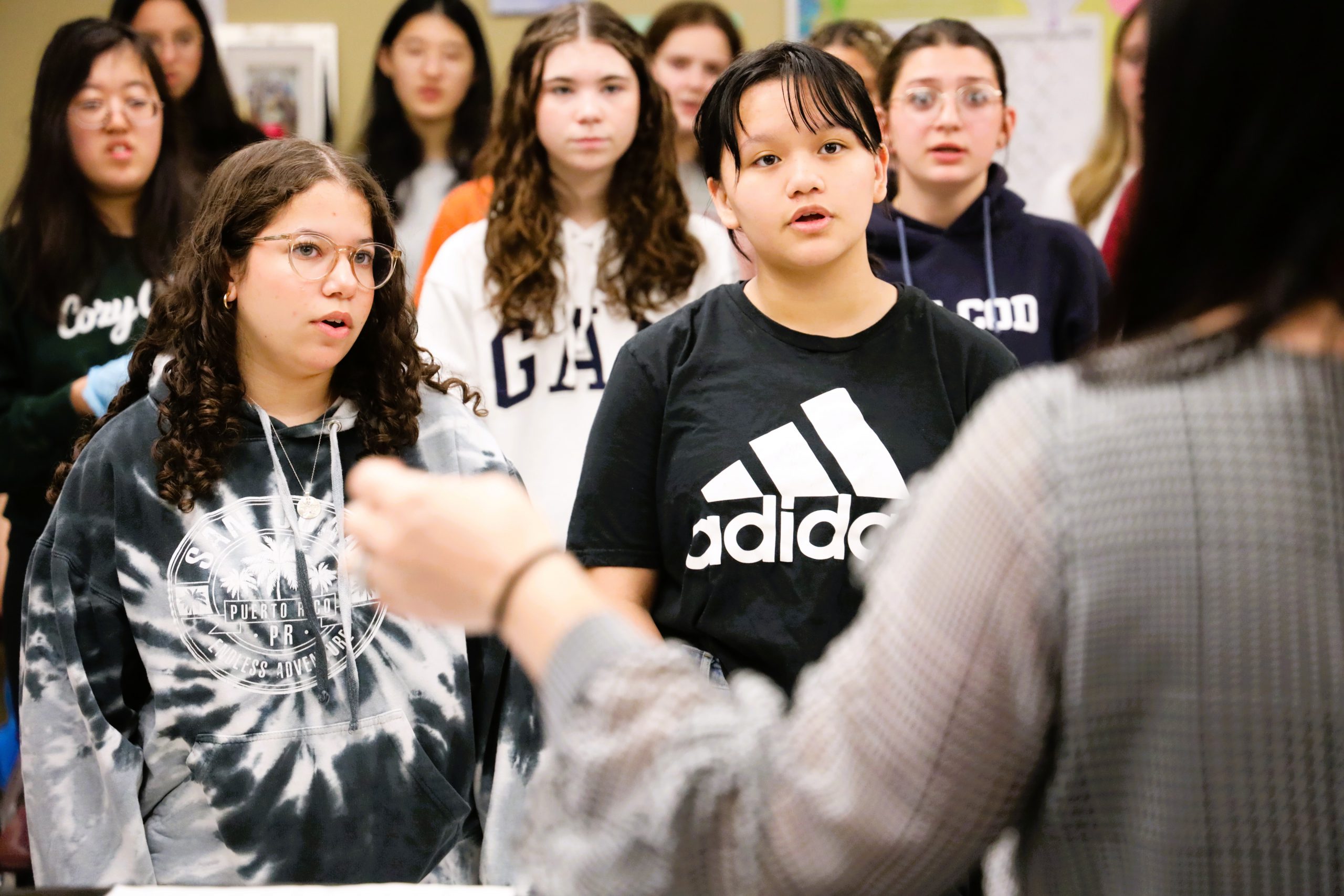 Students look towards music instructor while singing.