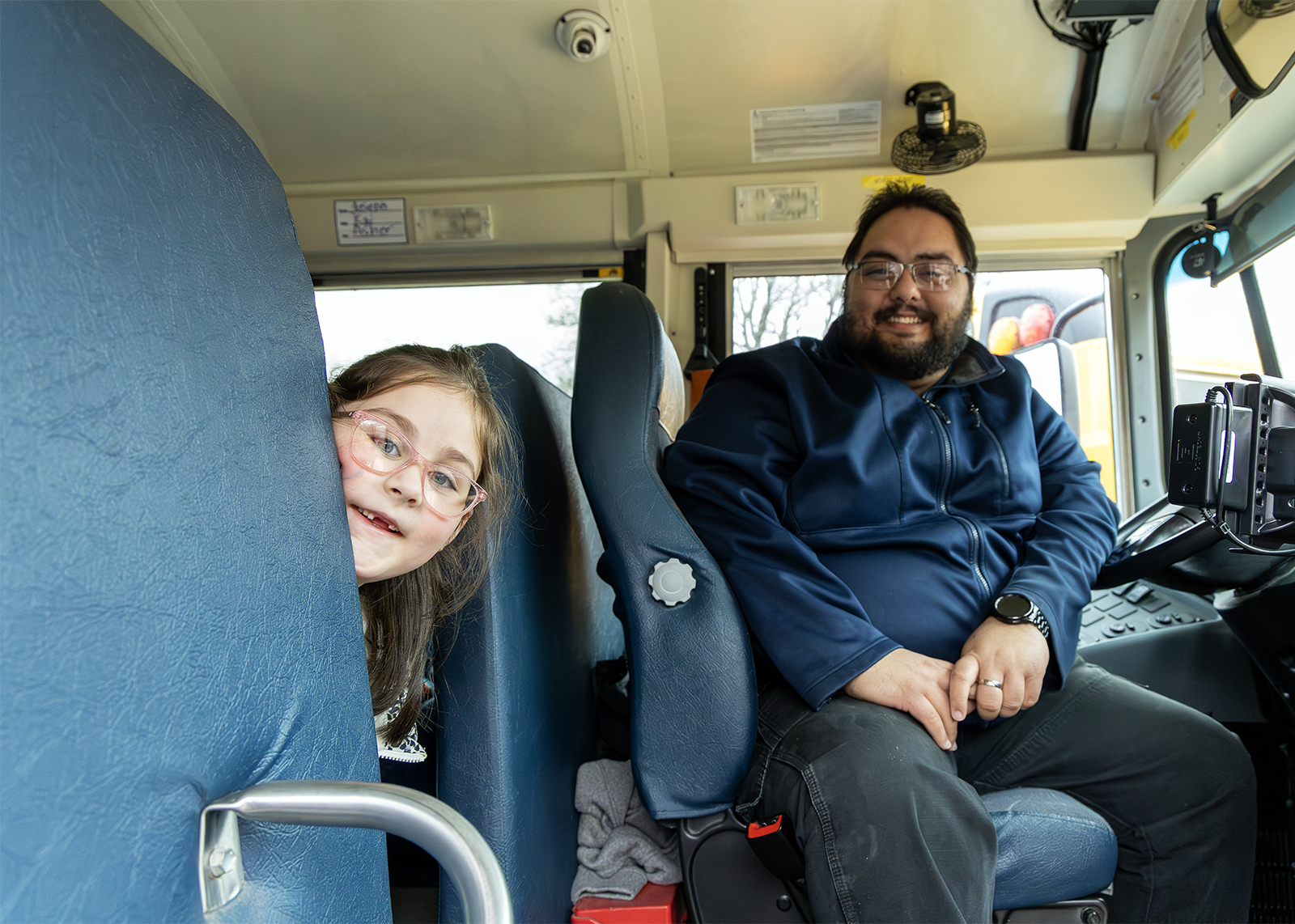elementary student peek around front seat on bus