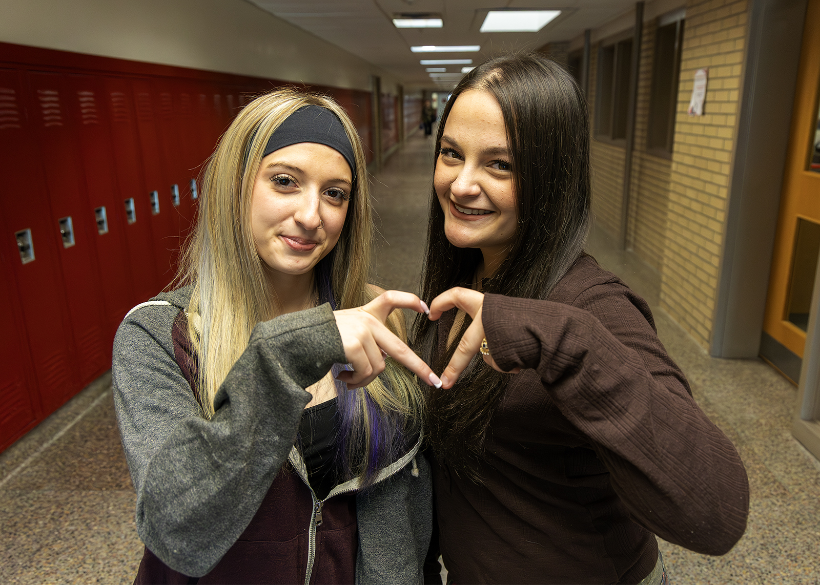 two high school students make a hand heart together