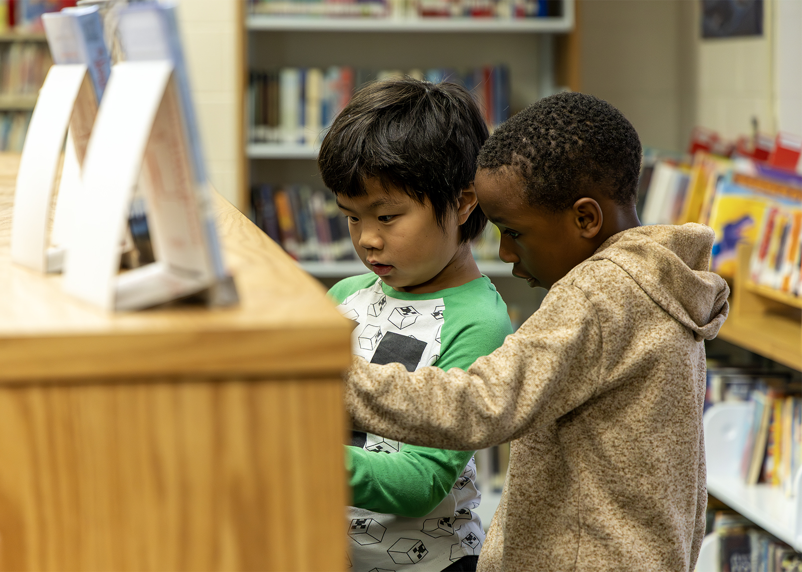 elementary students pick out books in library