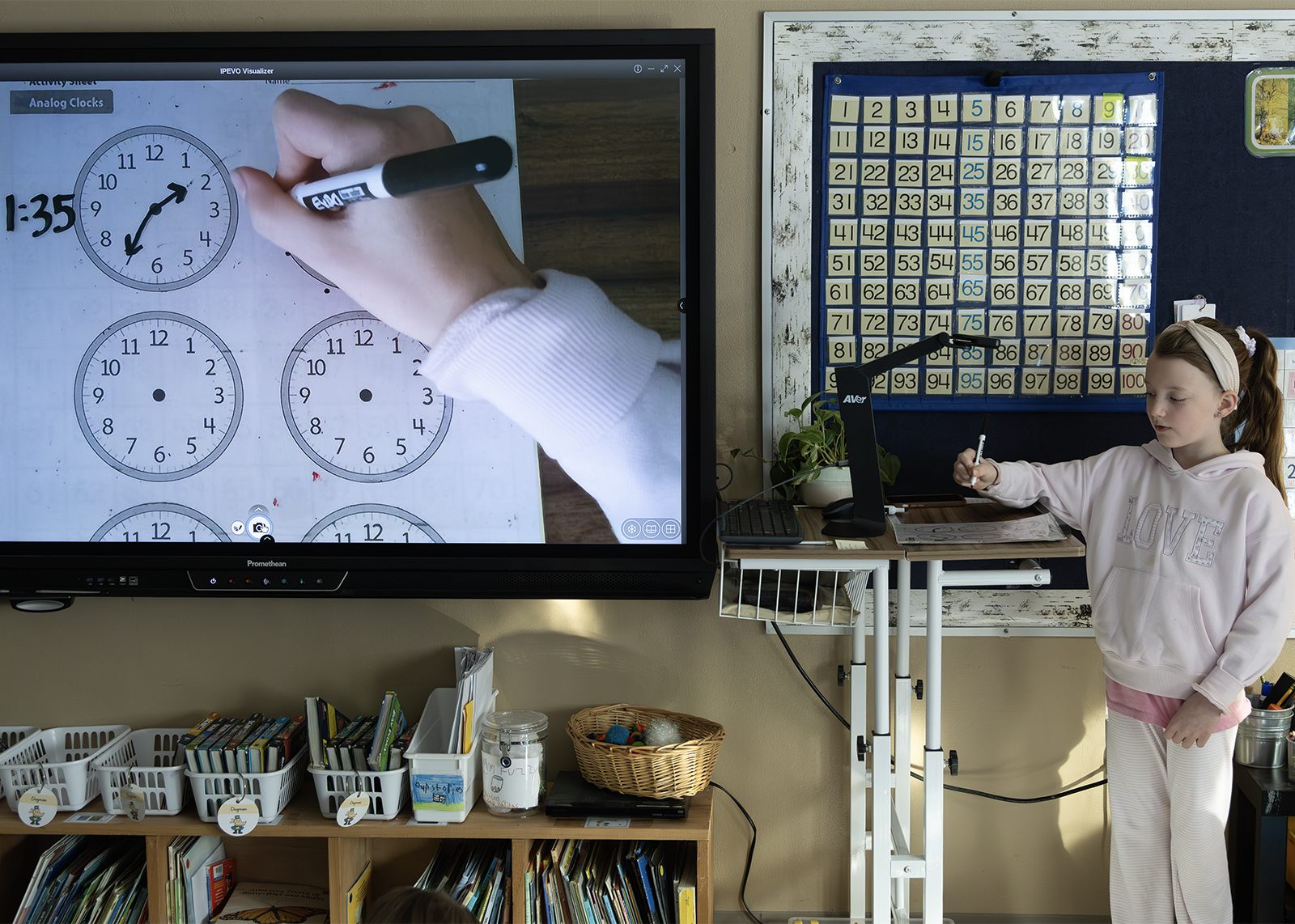 elementary student works on telling time activity at document camera