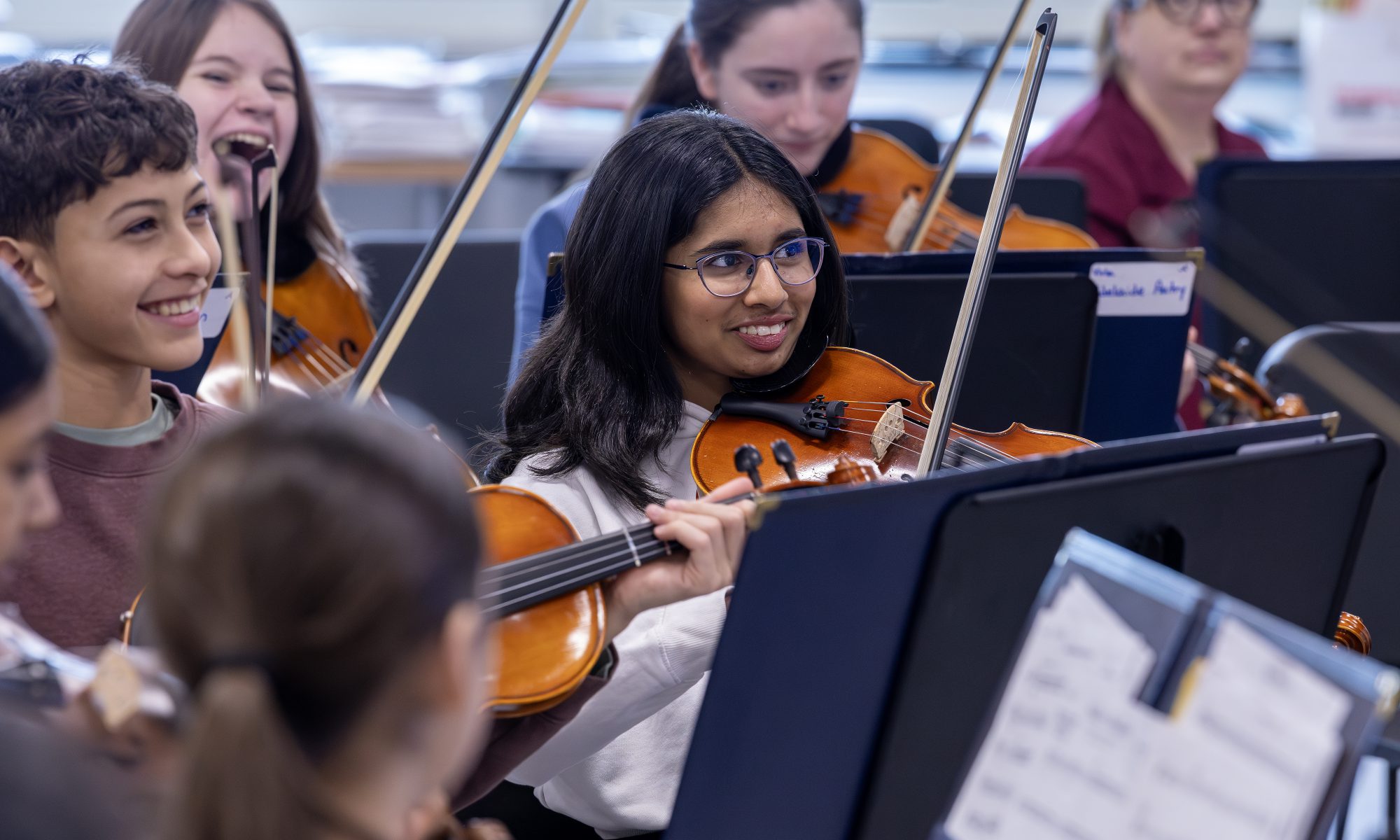 A class of middle school students playing string instruments