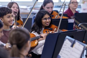 A class of middle school students playing string instruments 