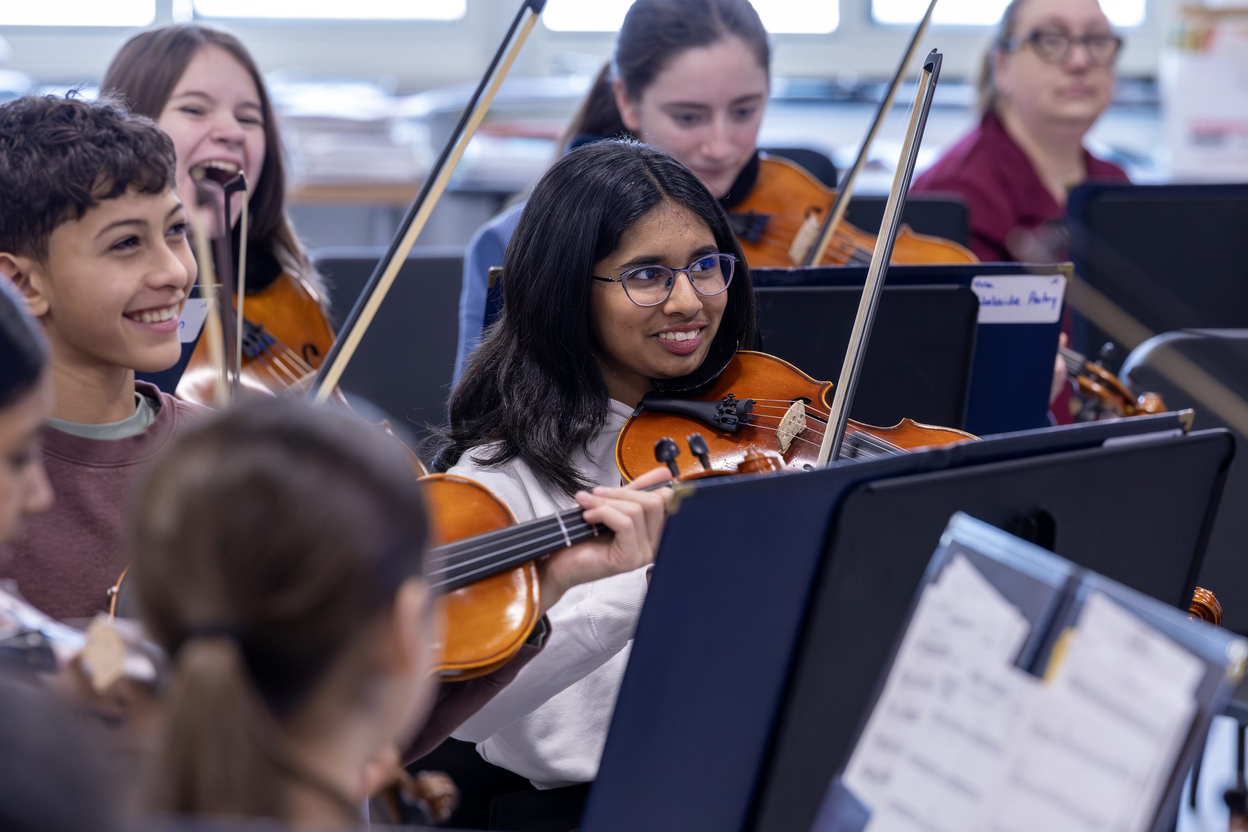 A class of middle school students playing string instruments