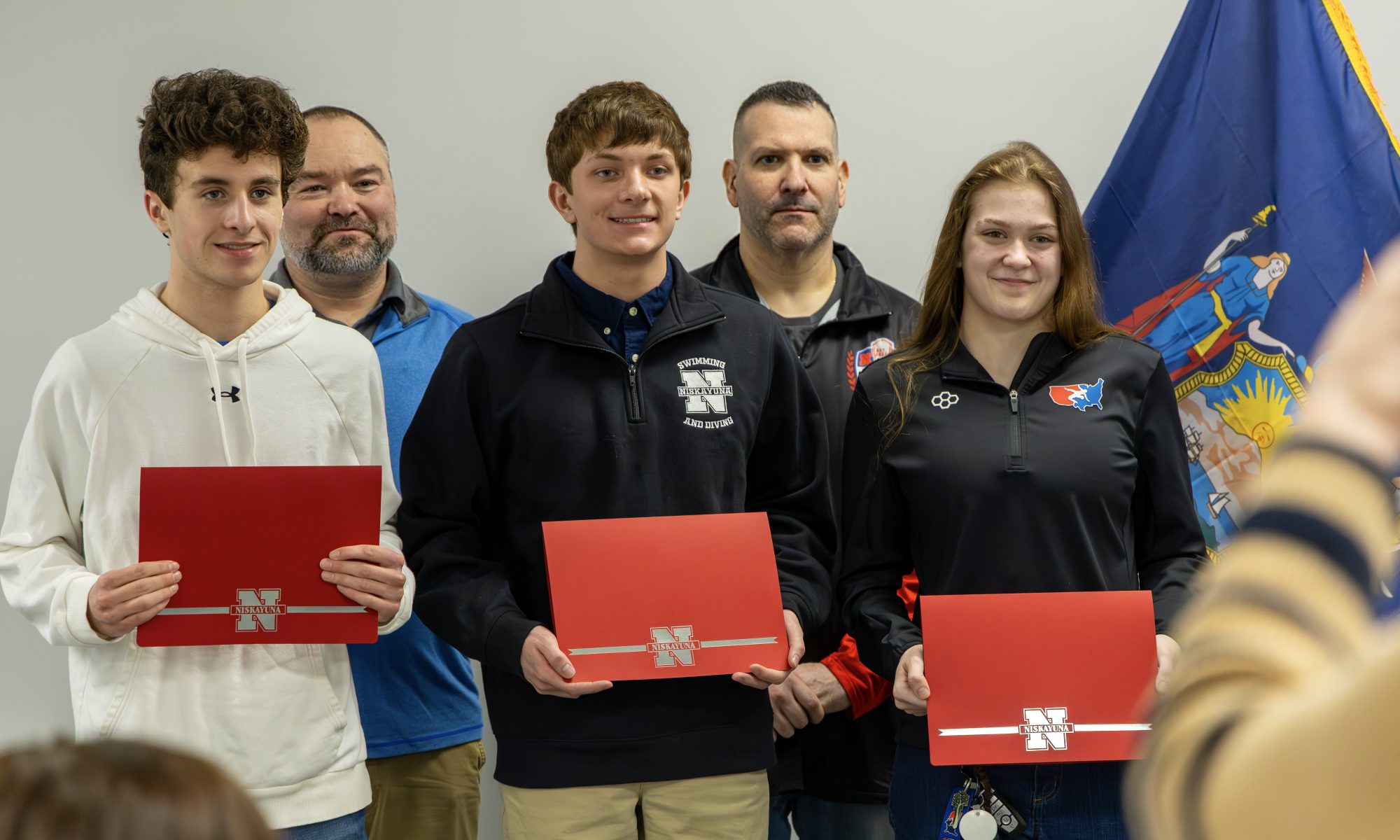 Three student athletes and two coaches of winter sports at the Board of Education meeting