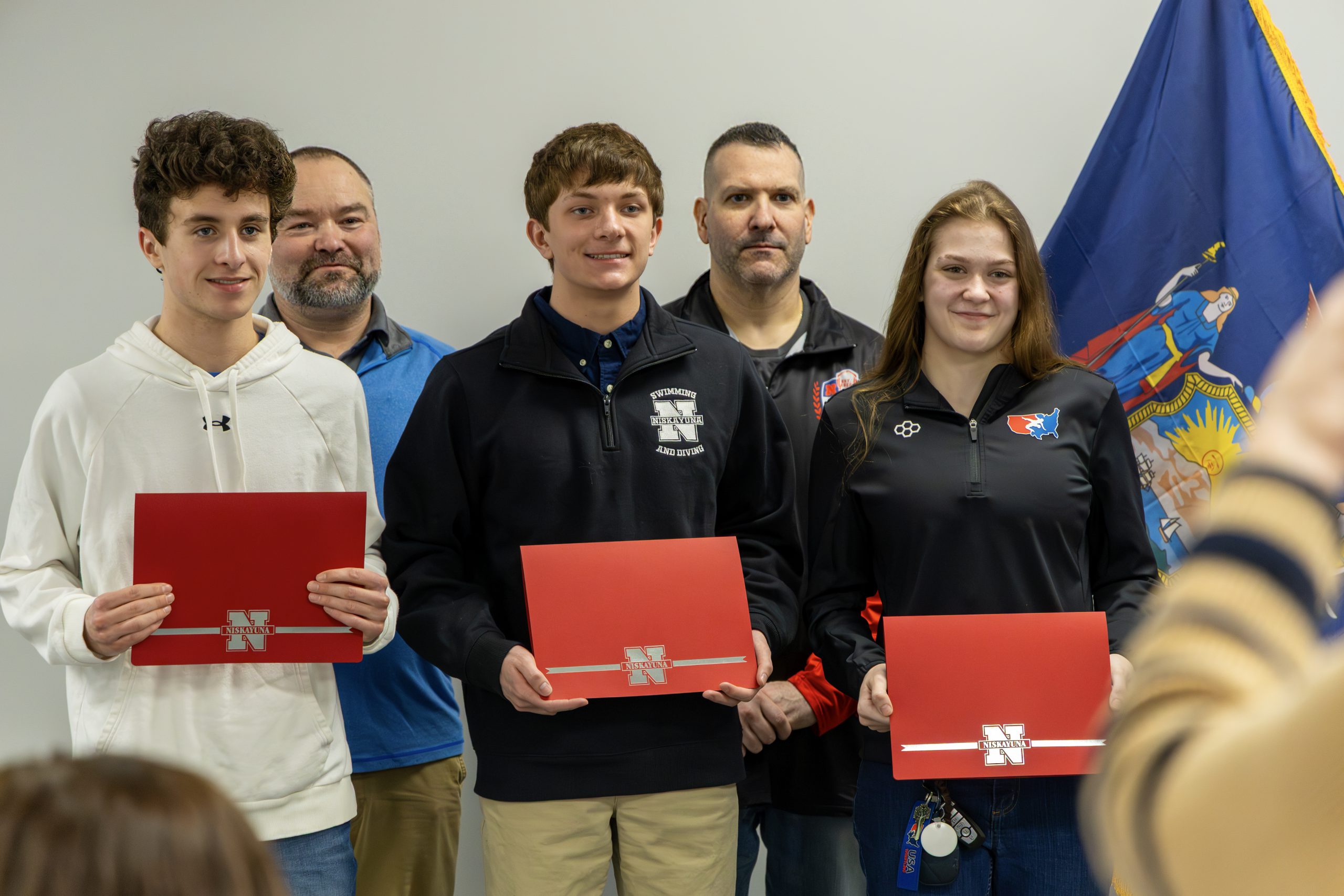 Three student athletes and two coaches of winter sports at the Board of Education meeting