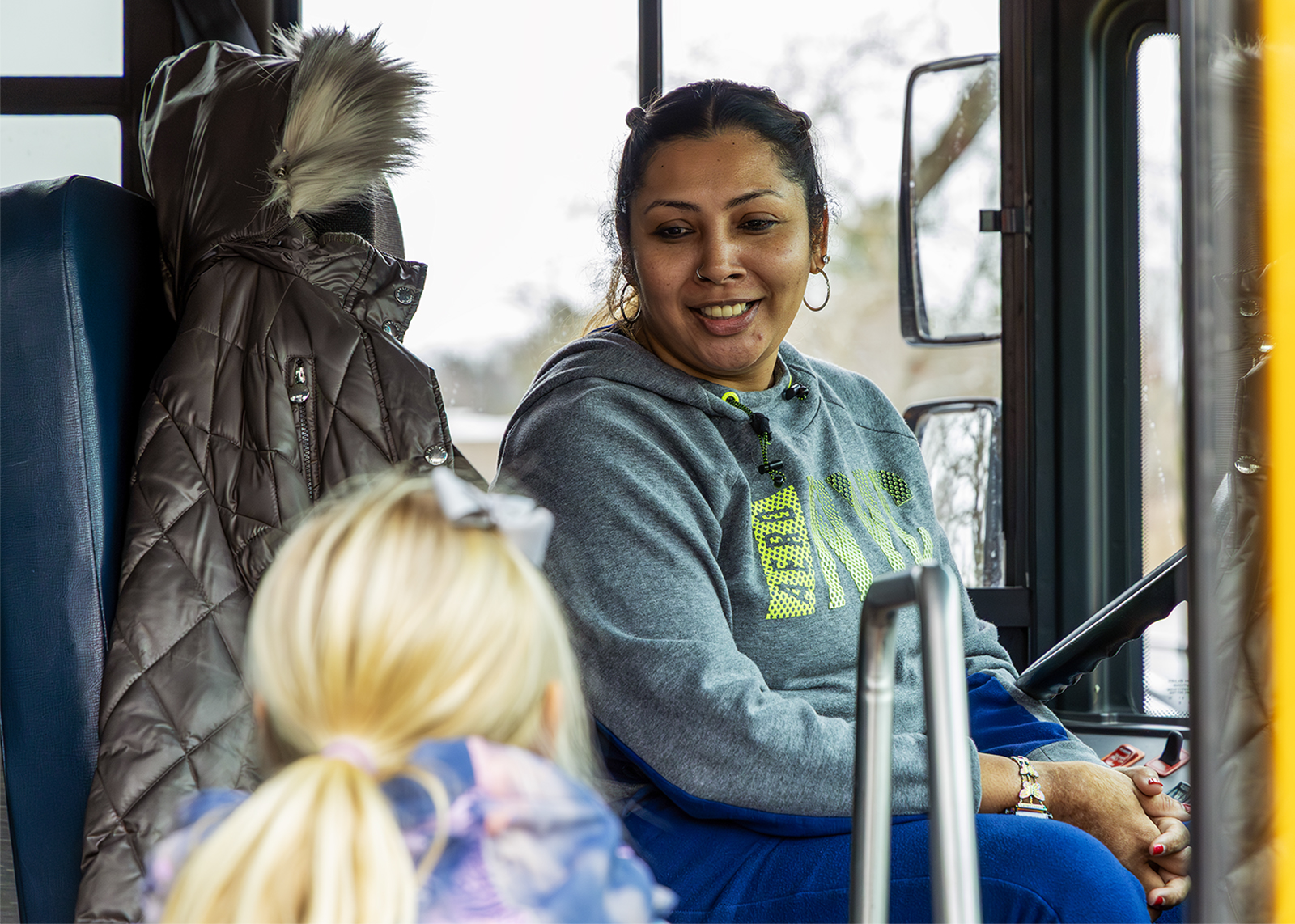 bus driver smiles at an elementary student getting on the bus