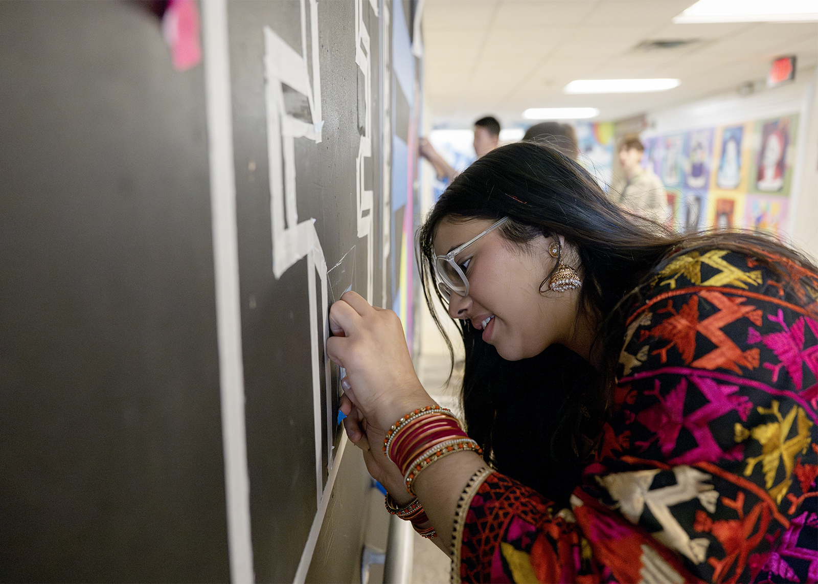 high school student working on a wall mural