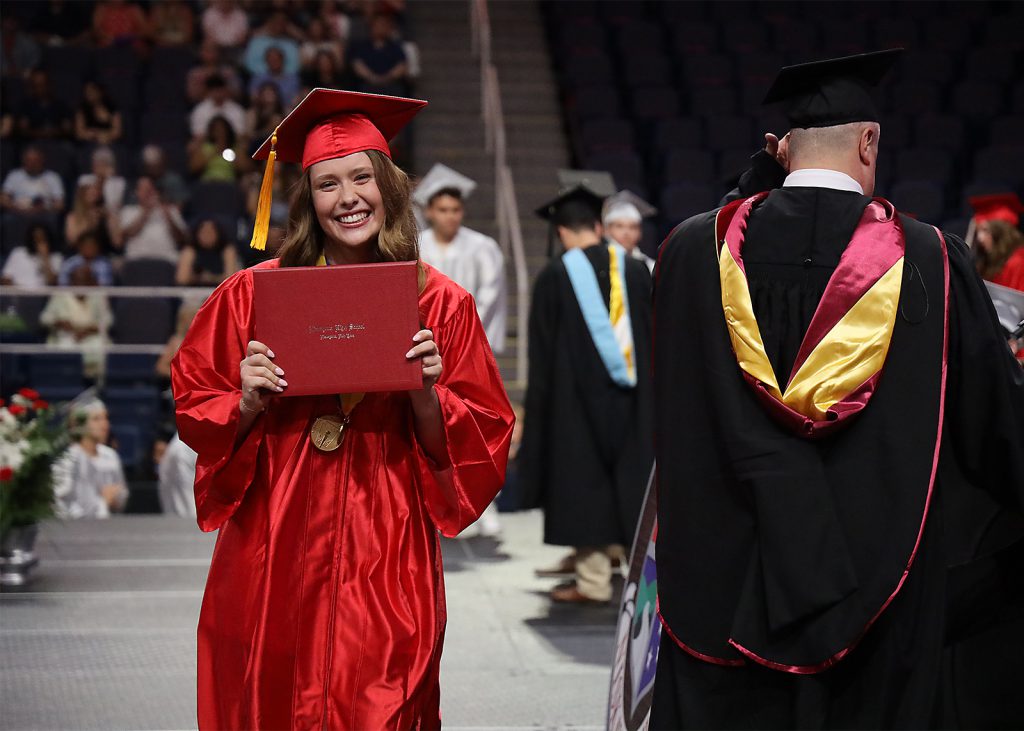 Graduate smiling with Diploma in hand.