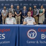 Two students holding CTE signing day certificates at a ceremony table
