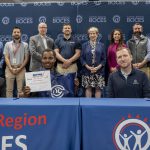 A student holding CTE signing day certificates at a ceremony table