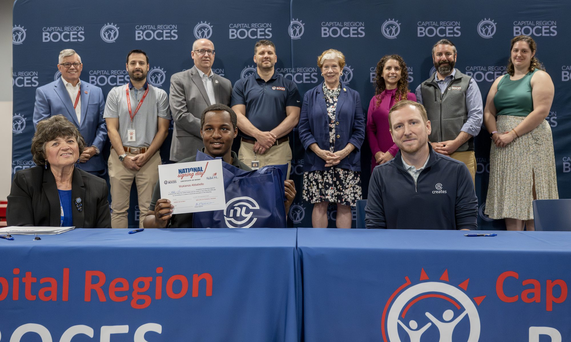 A student holding CTE signing day certificates at a ceremony table