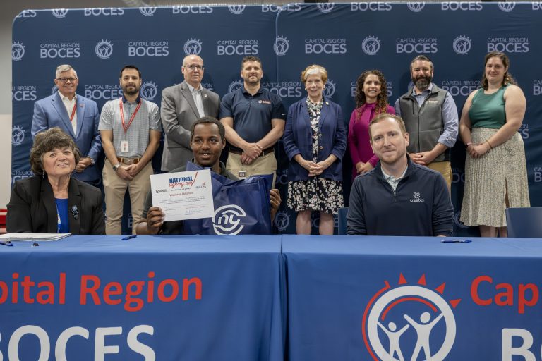 A student holding CTE signing day certificates at a ceremony table