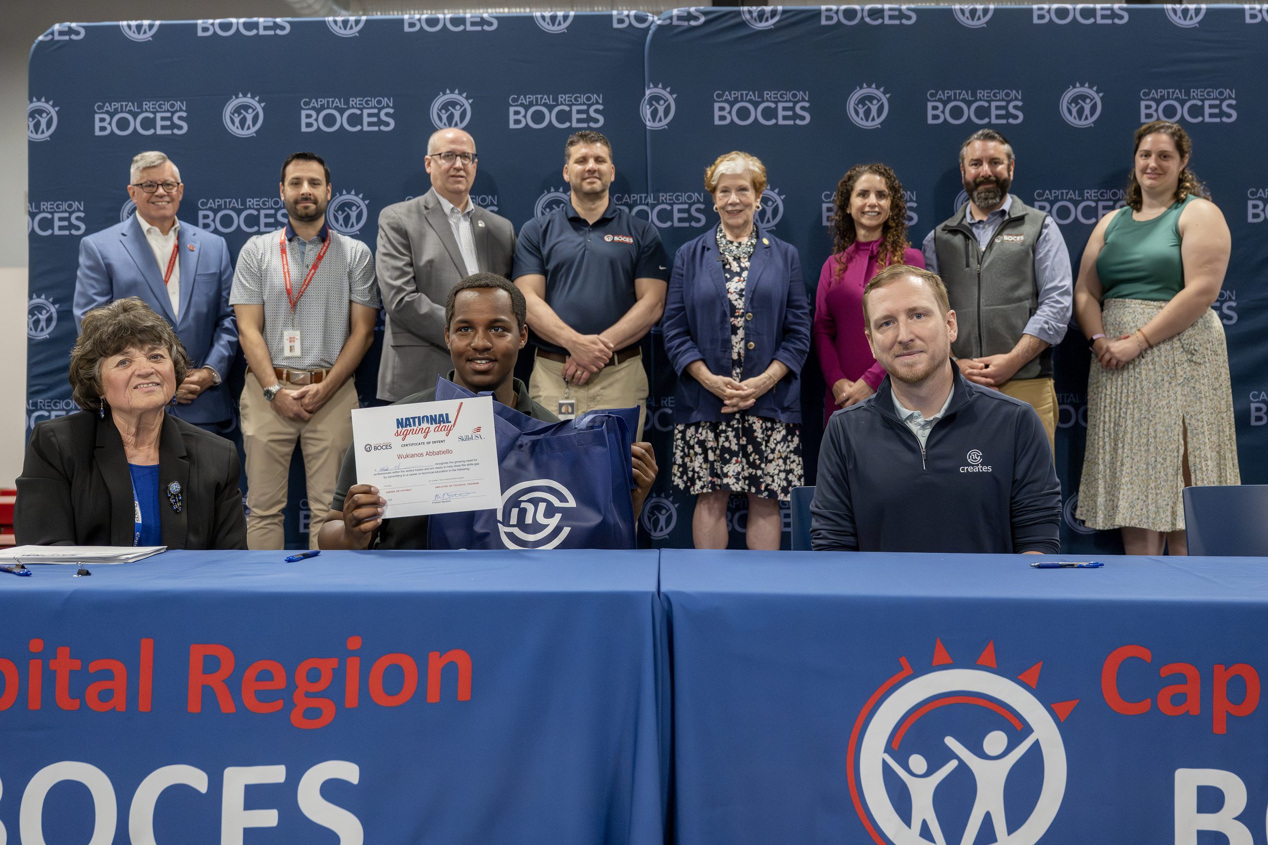 A student holding CTE signing day certificates at a ceremony table