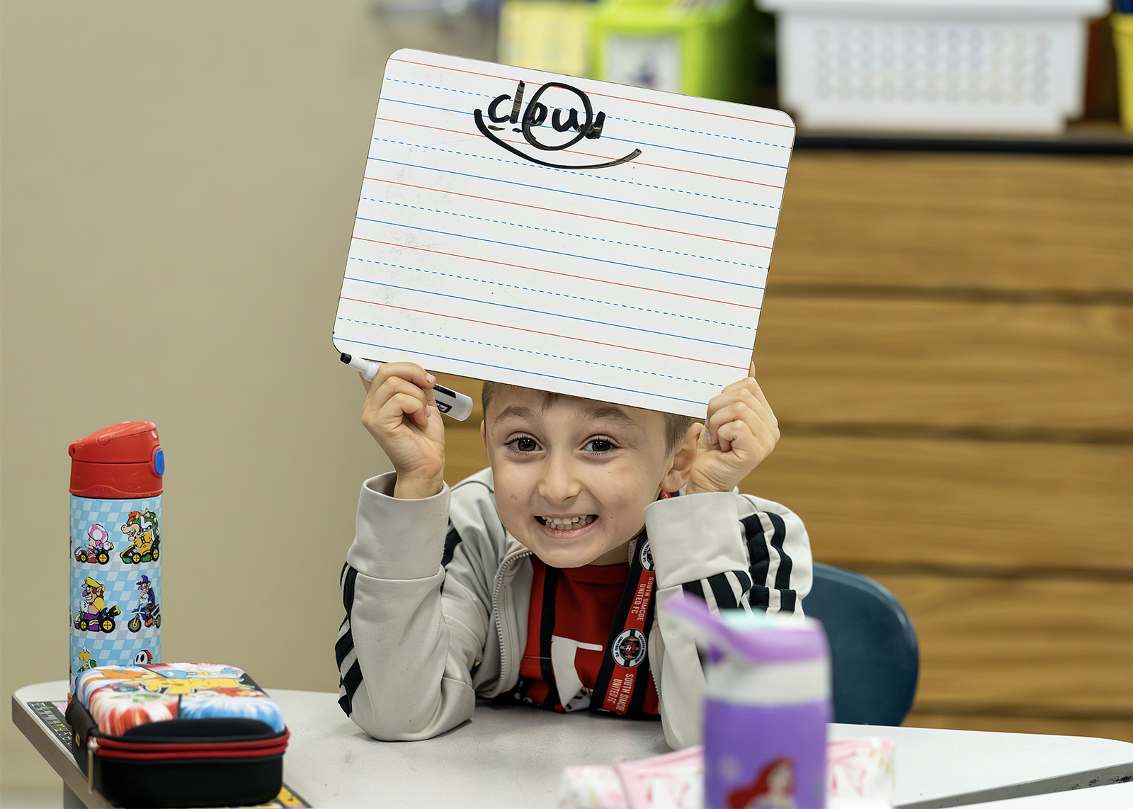 an elementary student holding up a dry erase board with ELA words