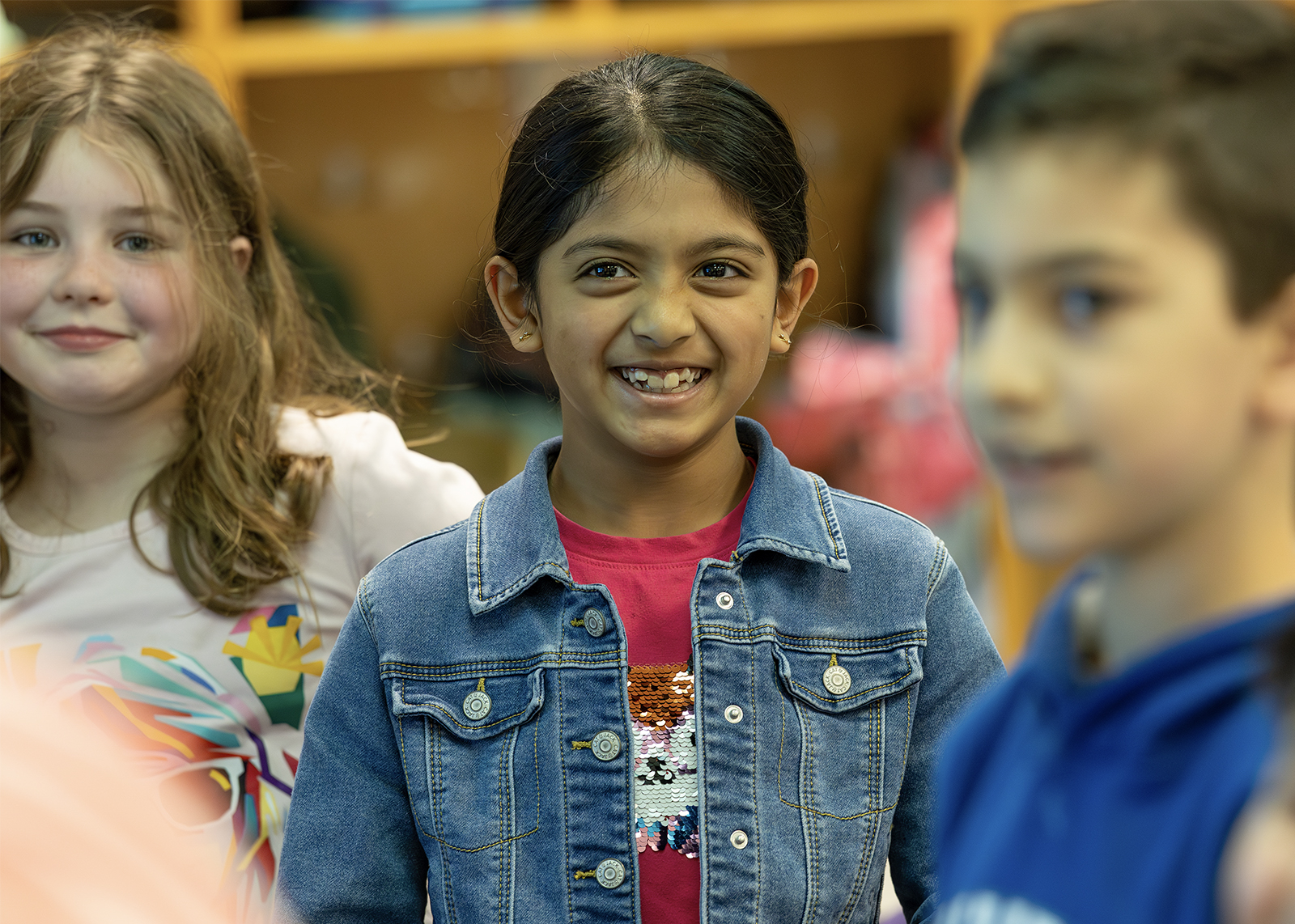 student wearing jean jacket smiling at camera