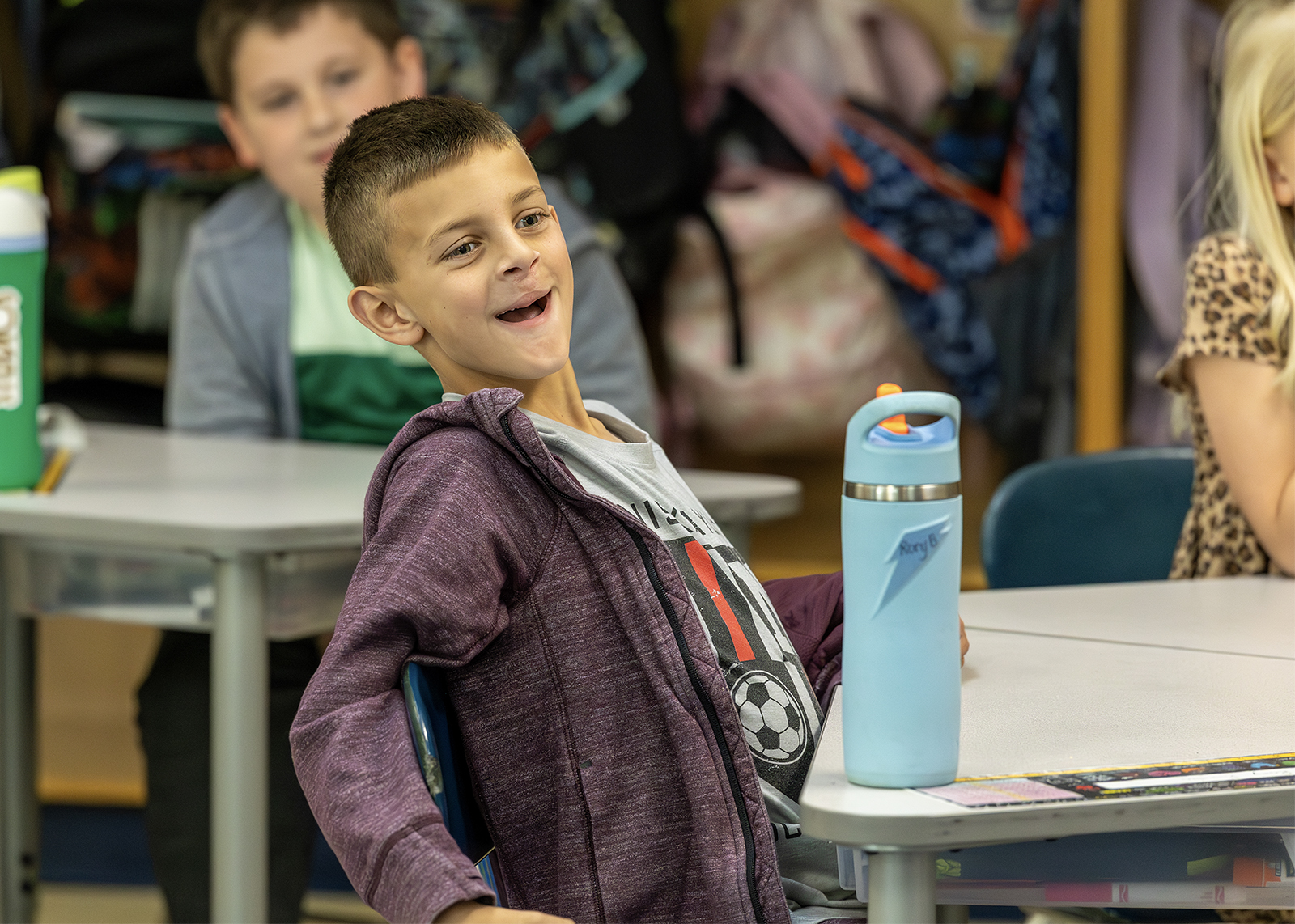 student looking happy and shocked in class with waterbottle on desk