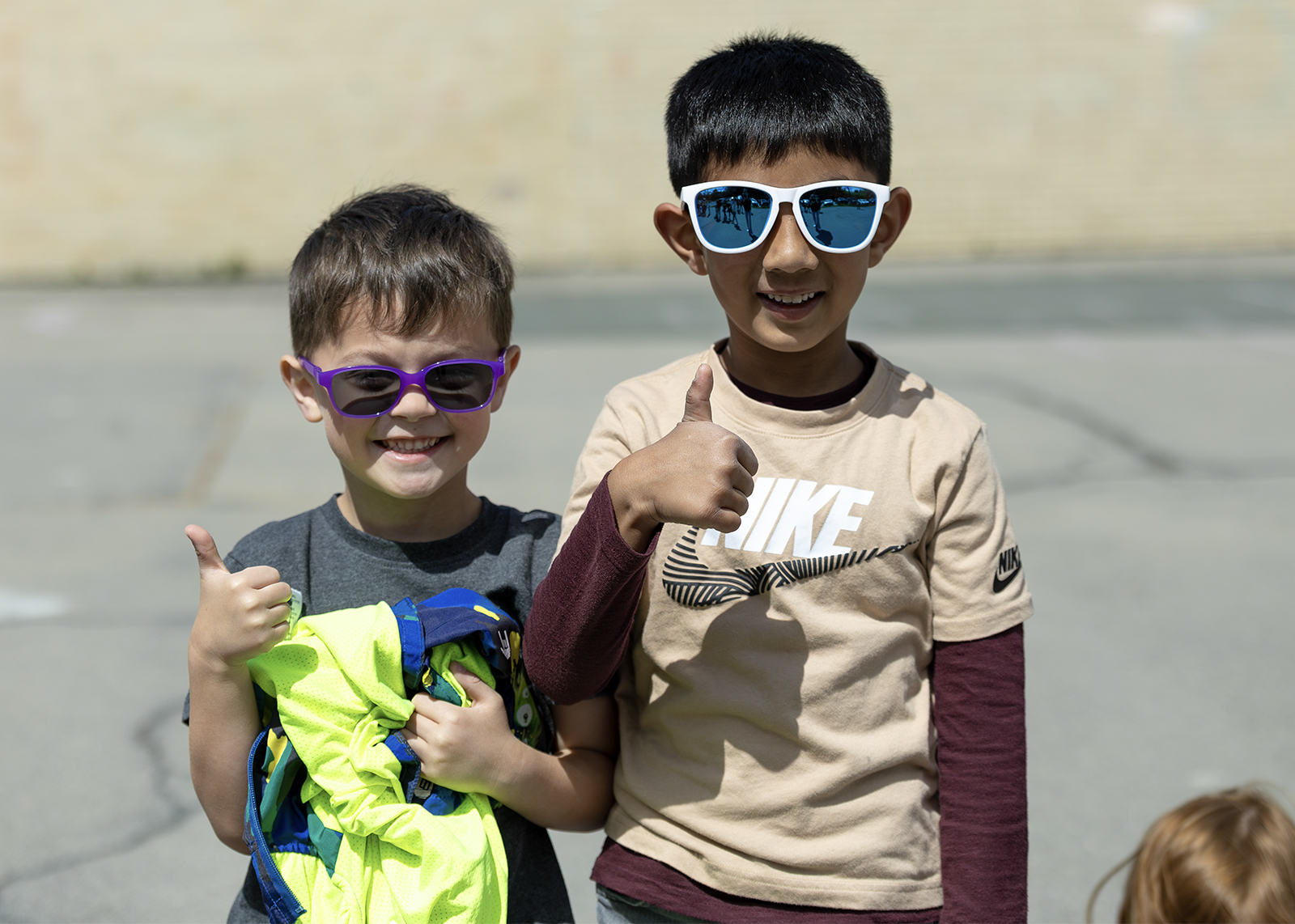 two kindergartners wearing sunglasses and giving humbs up at recess