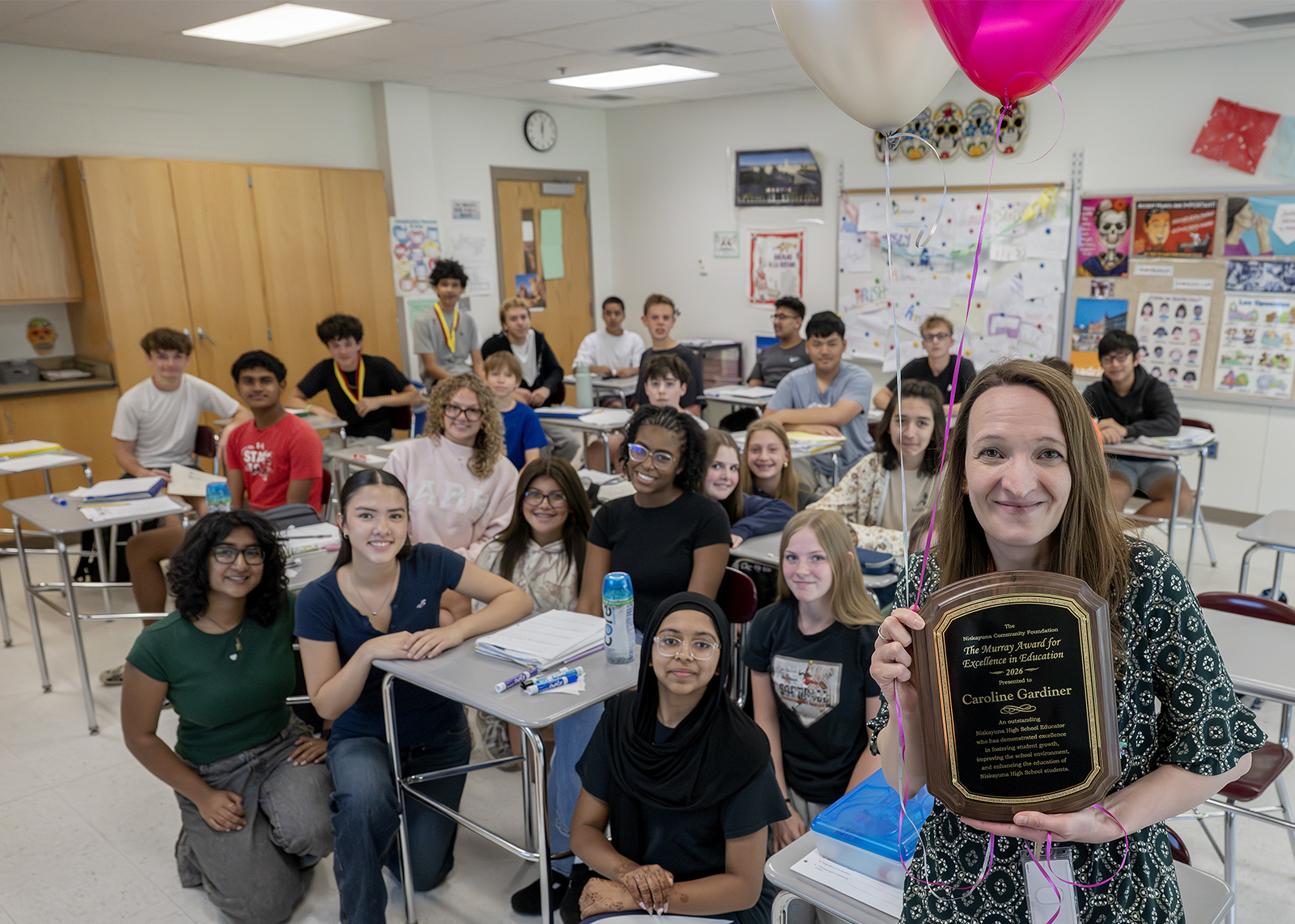 educator holding up Murray award plaque in front of classroom of kids